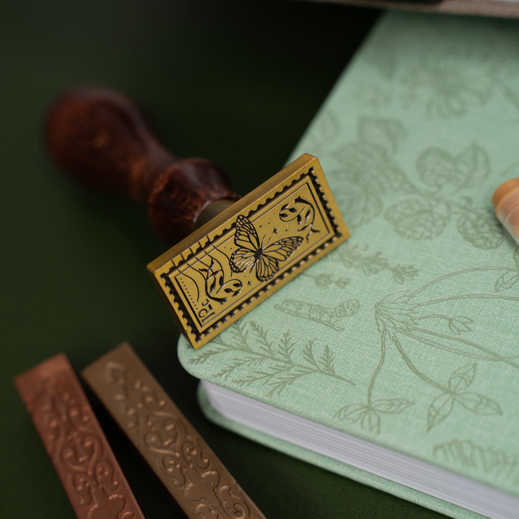Wooden stamp with butterfly design on a green notebook