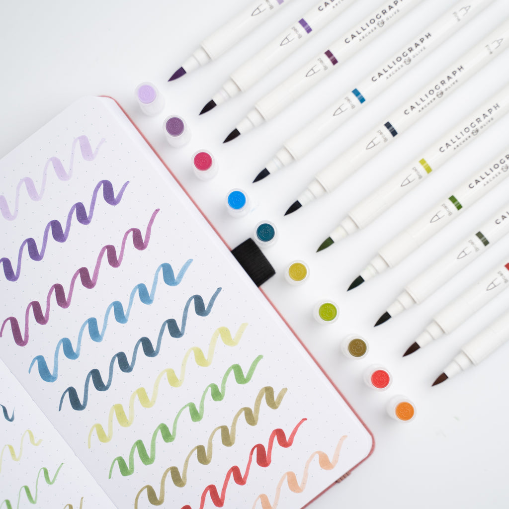 Set of Calligraphy markers with a sample of colorful calligraphy on paper