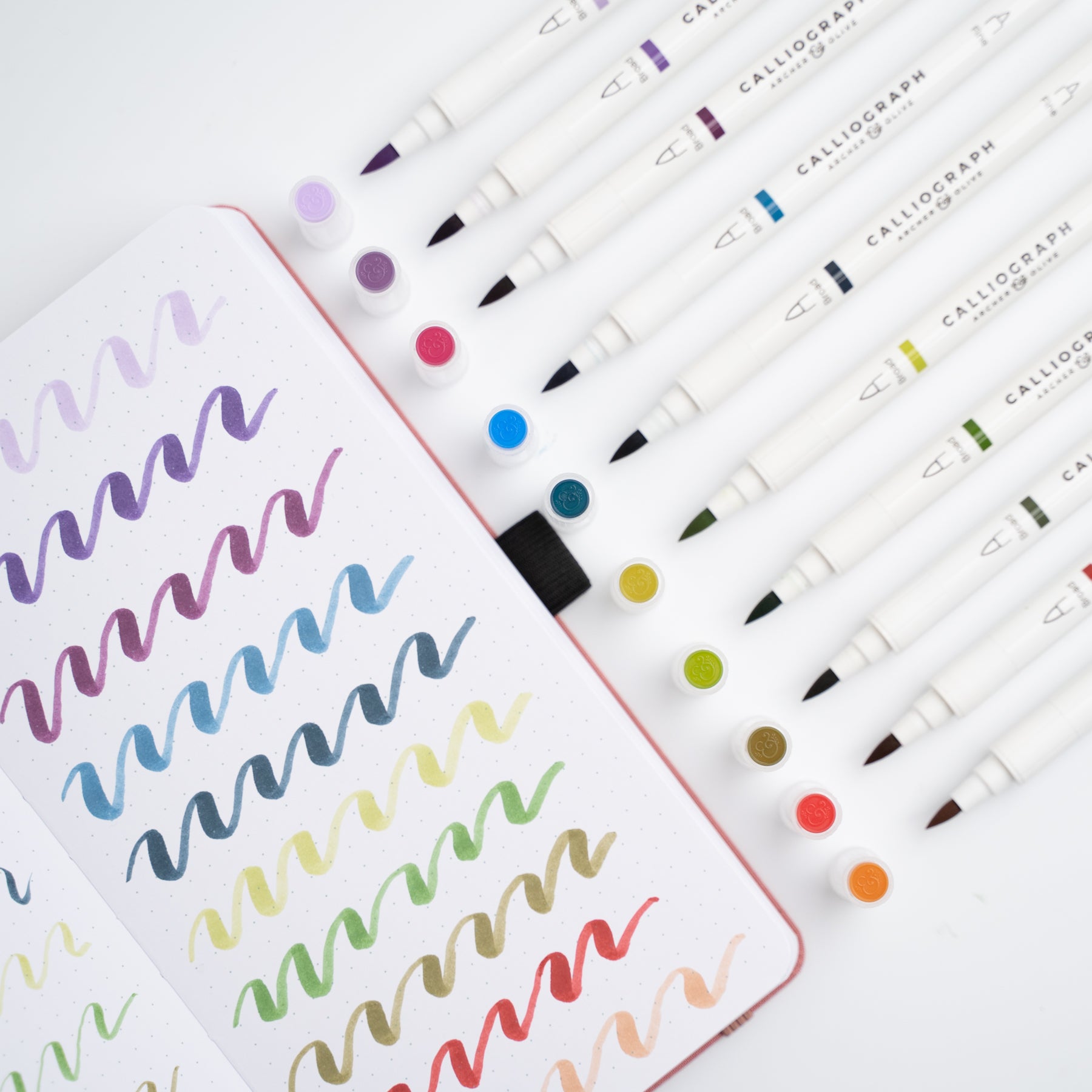 Set of Calligraphy markers with a sample of colorful calligraphy on paper