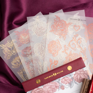 Sheets of rose gold and silver foil stickers with 'Archer & Olive' branding on a purple fabric background.