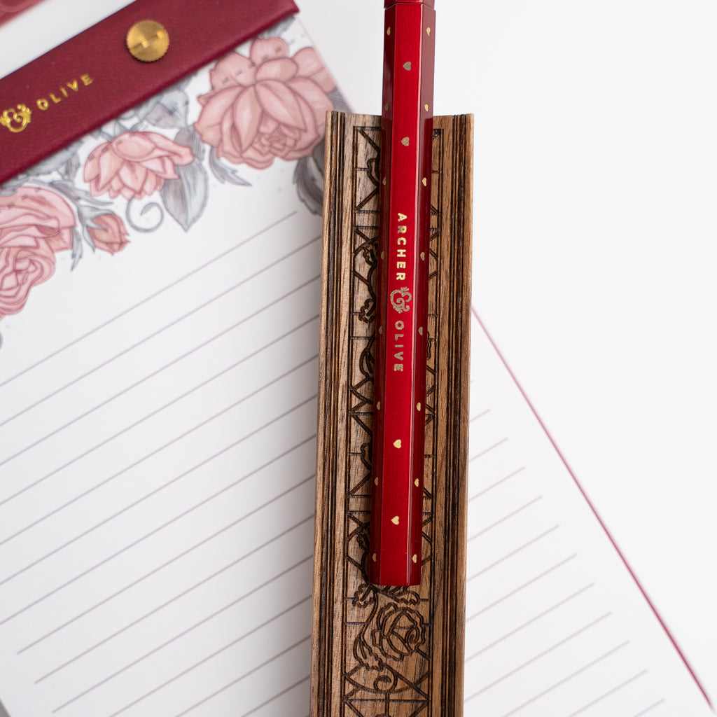 Red pencil with decorative casing on a floral notebook