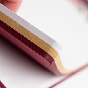 Close-up of notepad with White, Gold and Red pages